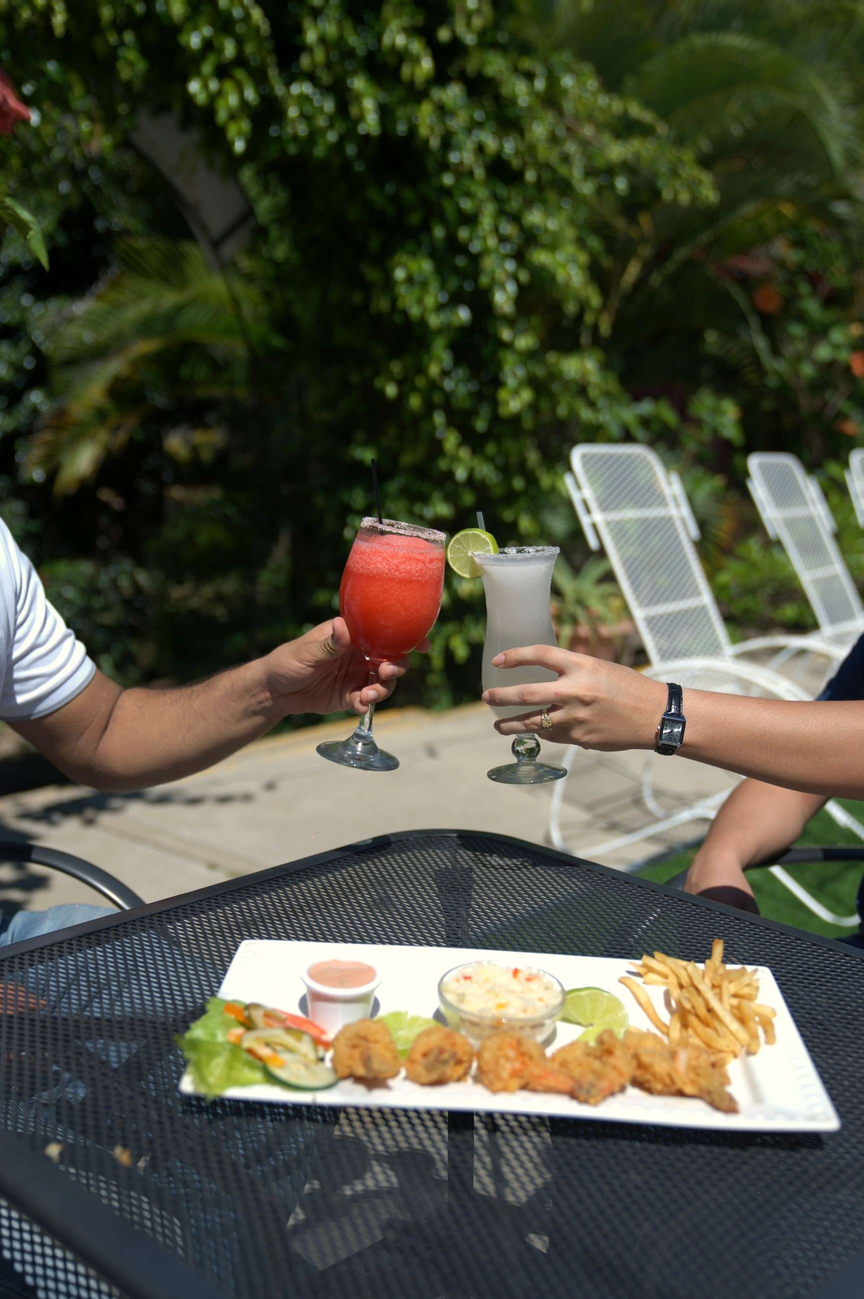 Dos personas brindando con bebidas heladas en el jardín del restaurante