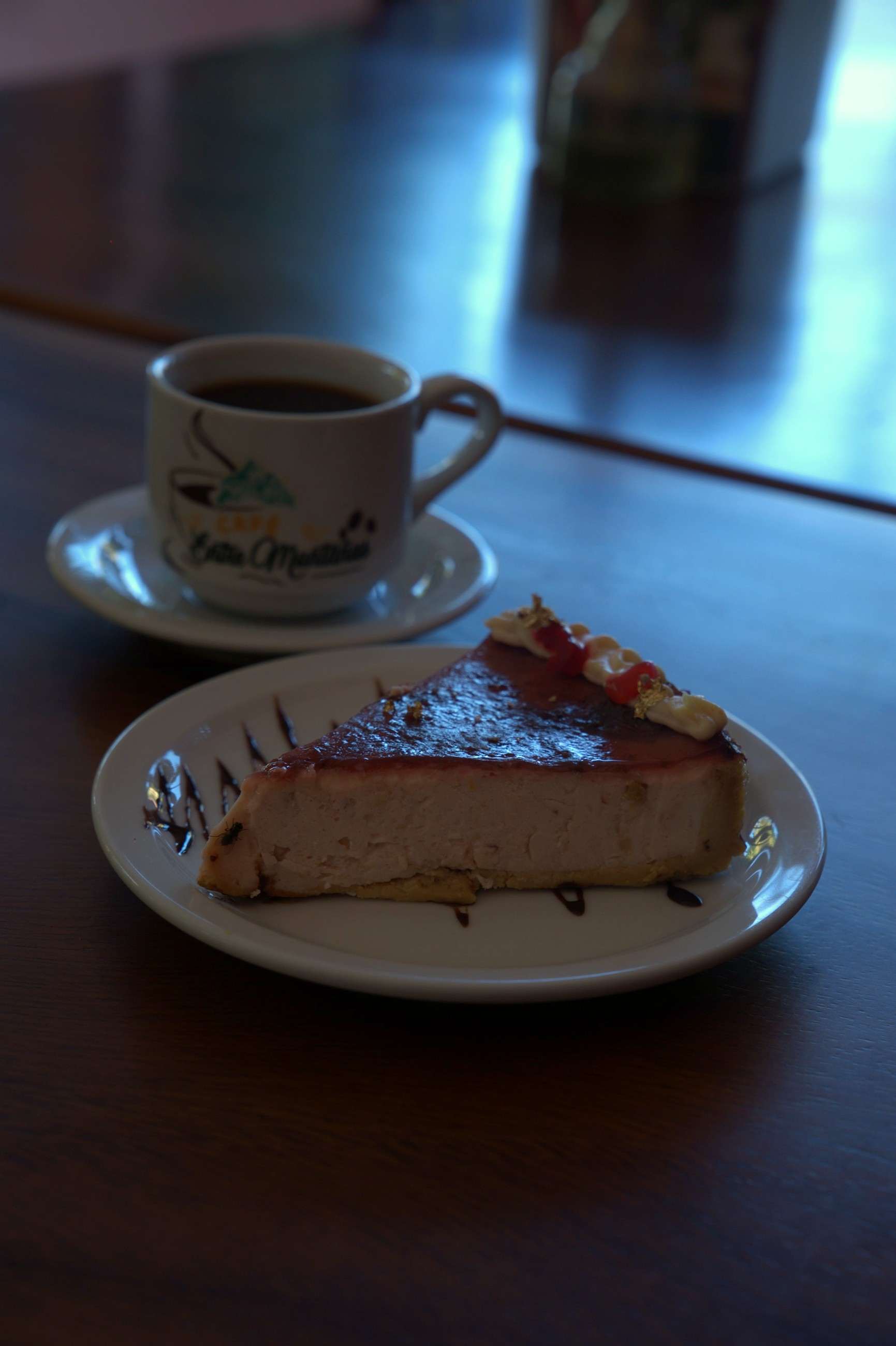 Taza de café y cheesecake con salsa de frutos rojos