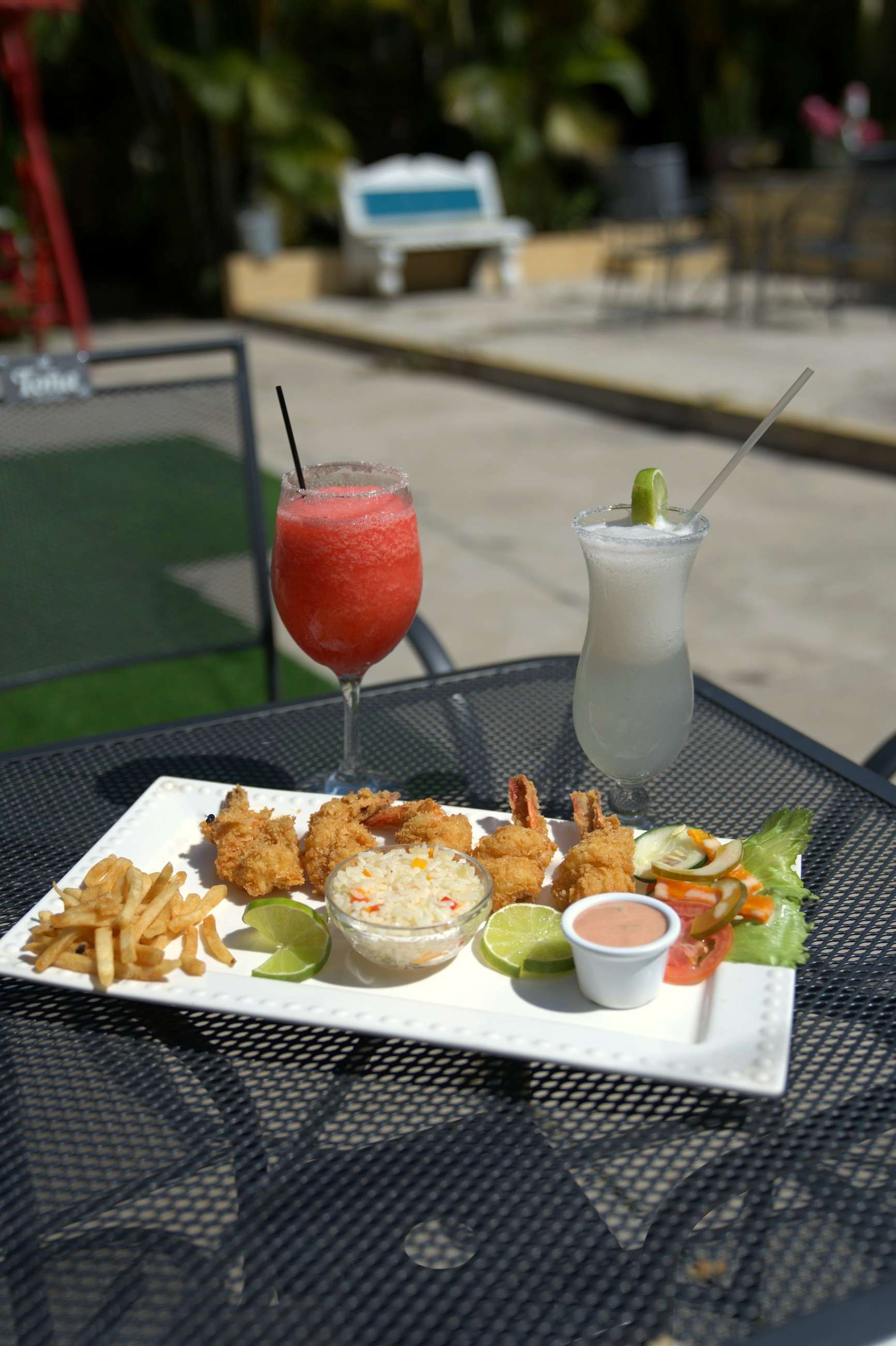 Breaded shrimp and two iced drinks on a terrace table