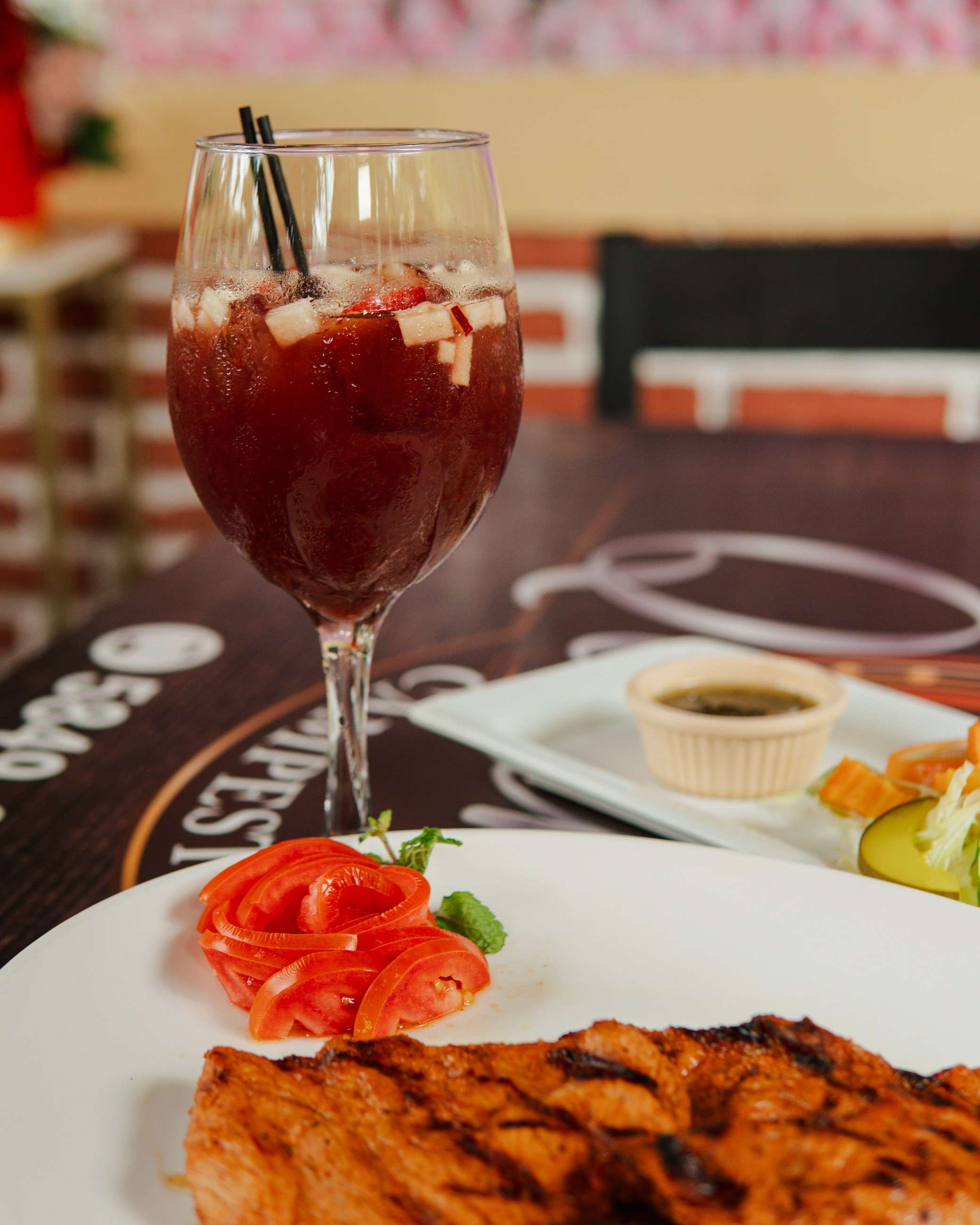 Copa de bebida con fruta junto a un plato a la parrilla